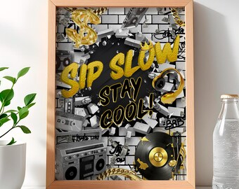 May include: A framed print with a black and white brick wall background. The wall is broken with gold accents and the words "Sip Slow Stay Cool!" in gold letters. The print includes a gold dollar sign, a gold crown, a gold record player, and a gold boombox.