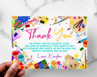 May include: Thank you card with a colorful art theme. The card features paintbrushes, paint tubes, and a paint palette with the words "Thank You" in pink and yellow. The text reads "My friend, for the colorful start. You made my birthday a true work of art! With brushes and paints, we had so much fun, creating memories, one by one! Love, Kendra."