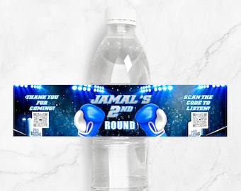 Könnte beinhalten: Blaues und schwarzes Wasserflaschenetikett mit Box-Motiv. Das Etikett lautet "Jamal's 2nd Round" mit blauen Boxhandschuhen auf beiden Seiten des Textes. Das Etikett enthält auch einen QR-Code und den Text "Vielen Dank für Ihr Kommen!" und "Scannen Sie den Code zum Anhören!"