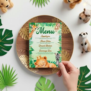 A hand is holding a menu with a jungle theme, surrounded by various stuffed animals and tropical leaves.
