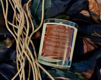 Może przedstawiać: Szklany słoik z przezroczystego szkła z brązową etykietą z napisem "House of Mahogany Transform Your Space From The Winter Scent Collection Midnight Ember Established 2020".
