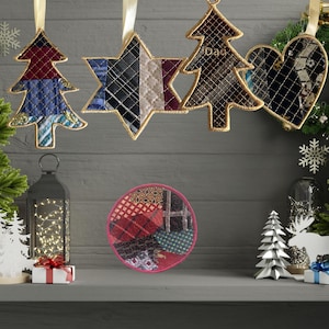 May include: Christmas decorations including tree, star, and heart-shaped ornaments made from patterned fabric with gold trim. A round coaster with a pink border and fabric patchwork is also visible. The ornaments are suspended by gold ribbons.