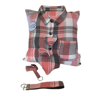 May include: A square pillow shaped like a button-down shirt in a pink, gray, and white plaid pattern. It features a collar, buttons, a chest pocket, a circular patch reading Always on my mind and in my heart, and a heart-shaped ornament labeled Dad.