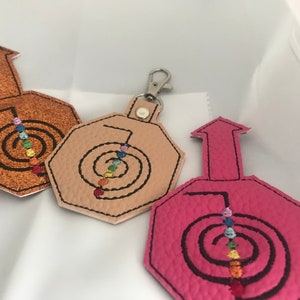 Può includere: Tre portachiavi con un design a spirale arcobaleno. I portachiavi sono in pelle e sono disponibili in marrone, beige e rosa.