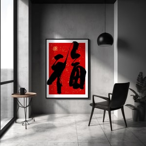 May include: A black and white calligraphy print of the Chinese character "福" (f&uacute;), meaning "good fortune" or "happiness", on a red background with gold accents. The print is framed and hanging on a gray wall in a modern interior.