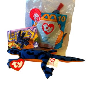 May include: A blue and orange Ty Beanie Baby named "Lizzy" the lizard. The Beanie Baby is in its original packaging with a McDonald's Happy Meal bag.