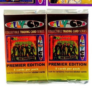 May include: A collection of vintage "Silly CDs" and trading card packs. The CDs feature album art with the text "NO TROUT" and "pristina-eggulera." Two packs of "NSTINK" trading cards are also visible, labeled "PREMIER EDITION."