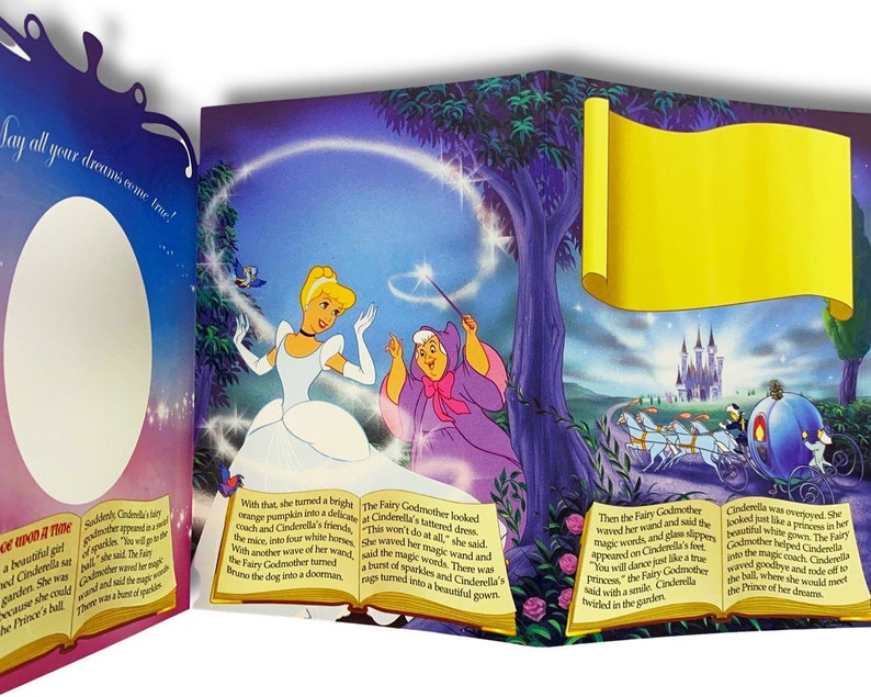 May include: A pop-up book illustration featuring Cinderella in a blue gown with a white petticoat, a fairy godmother in a purple gown, and a pumpkin turning into a carriage. The text reads "Say all your dreams come true!" and "This won't do at all."