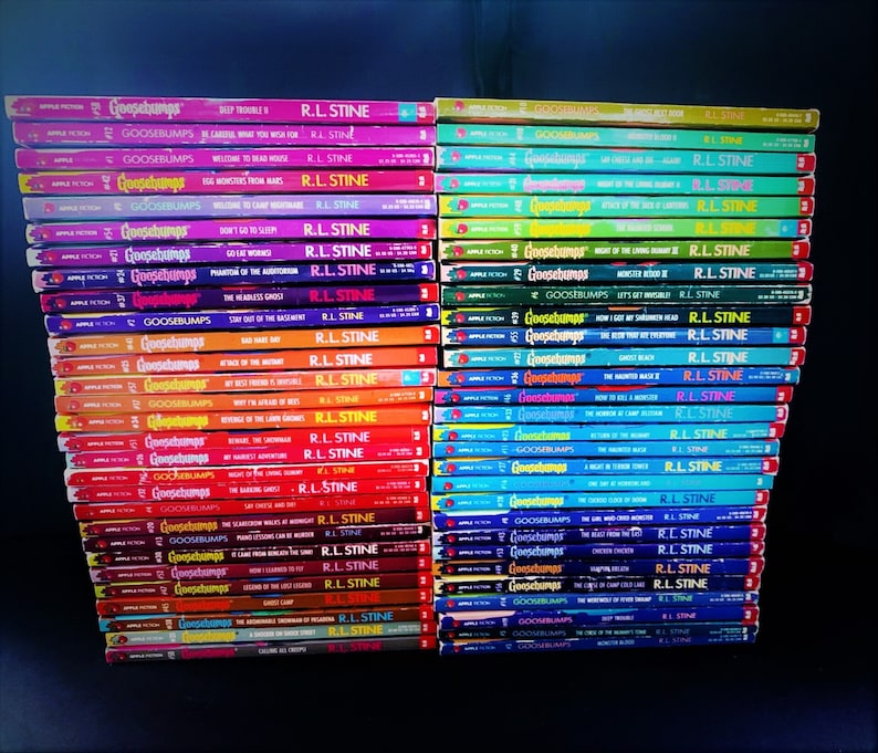 Pode incluir: Uma pilha de livros Goosebumps de R.L. Stine. Os livros est&atilde;o dispostos em duas colunas, com as lombadas voltadas para fora. Os livros s&atilde;o de cores diferentes, com t&iacute;tulos como "Deep Trouble", "Welcome to Dead House" e "Say Cheese and Die".