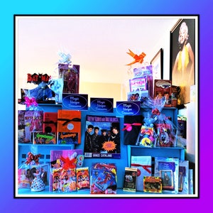 Pu&ograve; includere: Una collezione di regali confezionati e articoli in vendita, tra cui un libro intitolato "New Kids on the Block", un libro di Goosebumps, un CD delle Spice Girls e una statuetta di Batman. Gli articoli sono disposti su uno scaffale con ripiani blu e bianchi. Il cartello "Magic Unique Treasures" &egrave; ripetuto sullo scaffale.