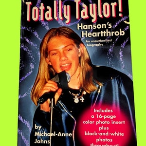 May include: A book cover titled "Totally Taylor! Hanson's Heartthrob" features a young person holding a microphone. The cover includes text that reads "An unauthorized biography" and "Includes a 16-page color photo insert plus black-and-white photos throughout!"