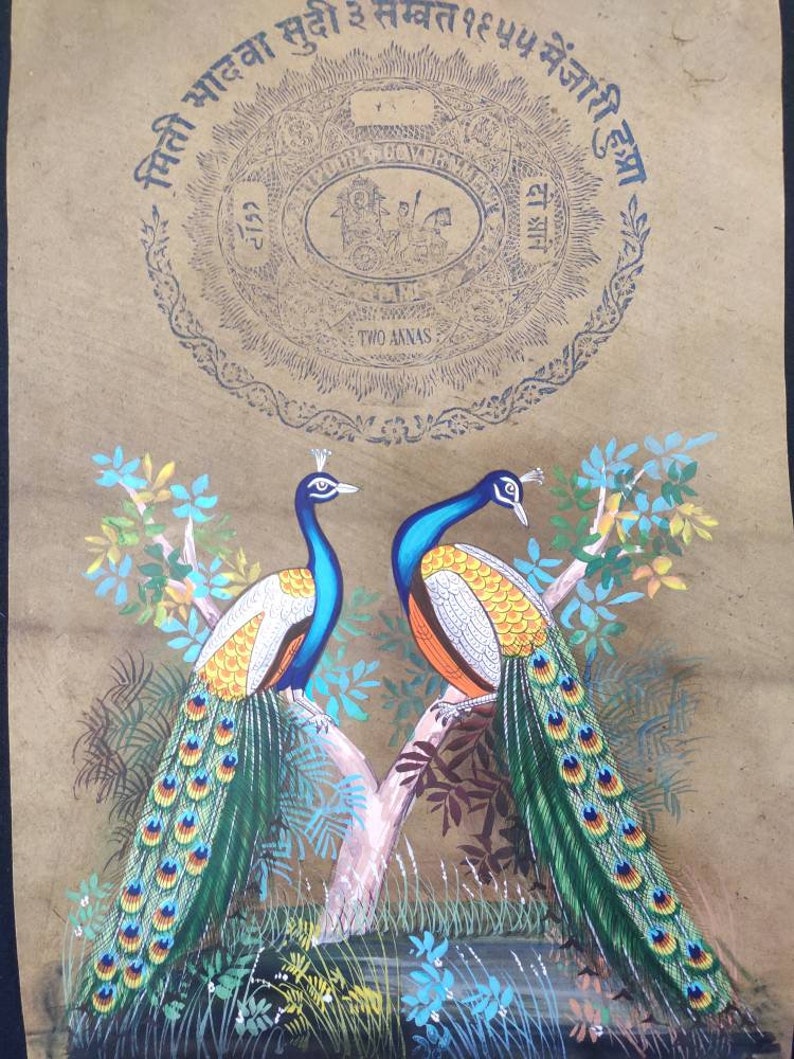 May include: An antique painting featuring two peacocks perched on a tree branch. The birds have blue heads, white and orange bodies, and vibrant green and blue tail feathers. The artwork includes text and a circular emblem at the top.