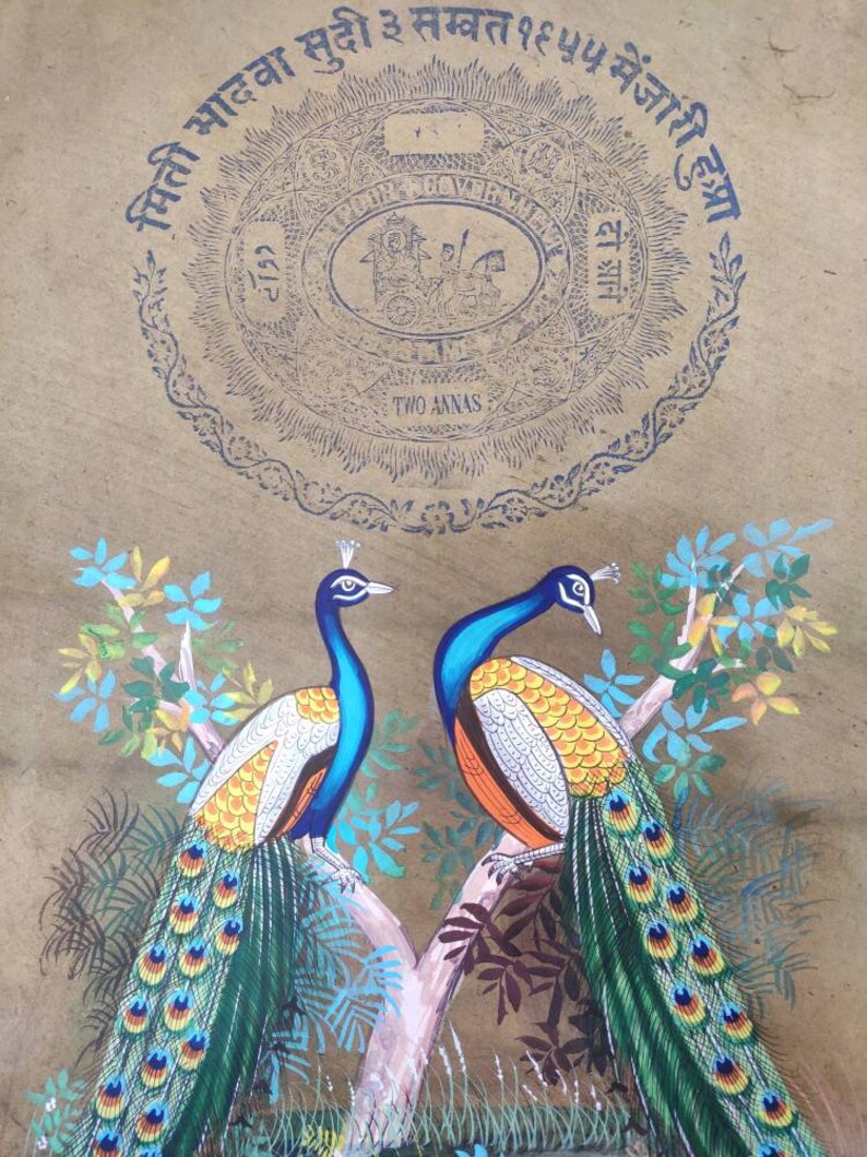 May include: A vintage painting featuring two peacocks perched on a tree branch. The birds have blue, green, and orange plumage. The background is a tan color with blue text and a circular design that reads "TWO ANNAS".