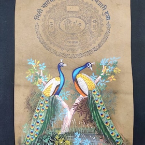May include: A vintage painting on tan paper depicts two peacocks perched on a tree branch. The birds have blue, yellow, orange, and green plumage. The artwork includes text in a circular design at the top, with the words "TWO ANNAS" visible.