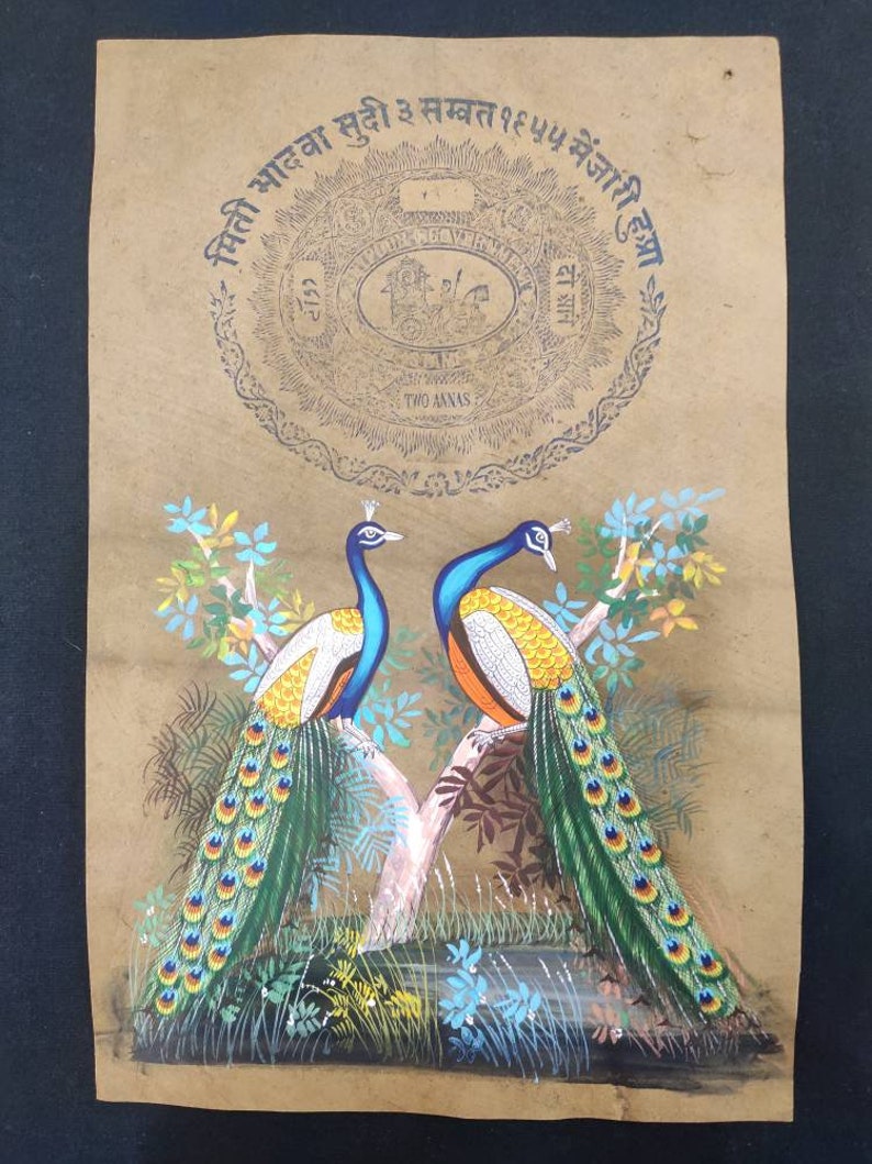 May include: A vintage painting on tan paper depicts two peacocks perched on a tree branch. The birds have blue, yellow, orange, and green plumage. The artwork includes text in a circular design at the top, with the words "TWO ANNAS" visible.