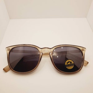 May include: A pair of brown tortoise shell sunglasses with polarized lenses. The sunglasses have a black frame and a gold label that says "Polarized UV Protection".