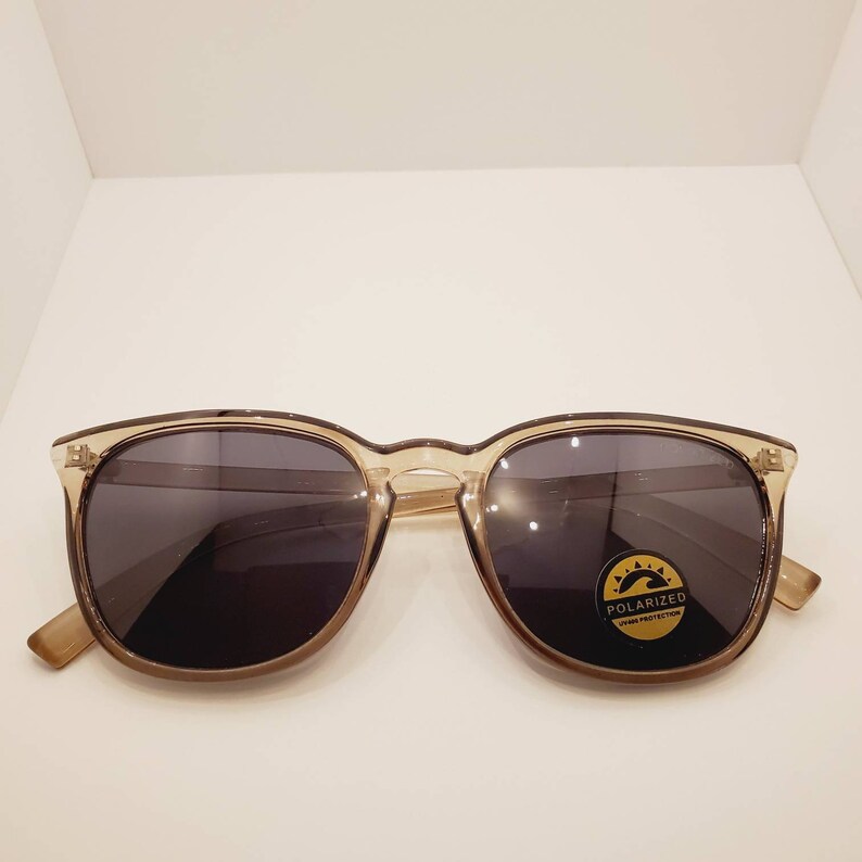 May include: A pair of brown tortoise shell sunglasses with polarized lenses. The sunglasses have a black frame and a gold label that says "Polarized UV Protection".