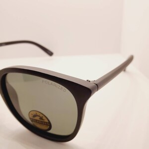 May include: Black sunglasses with polarized lenses. The sunglasses have a black frame and a silver label that says "POLARIZED".