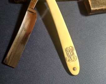 May include: A vintage straight razor with a white bone handle. The handle has an engraved monogram. The razor is in a brown leather case with the text "J.T. Nickel & Co." on the front.