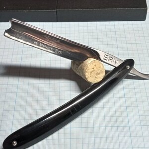 May include: A straight razor with a black handle and a silver blade. The blade is engraved with the text "G. & H. Fear ERN" and "ERN".