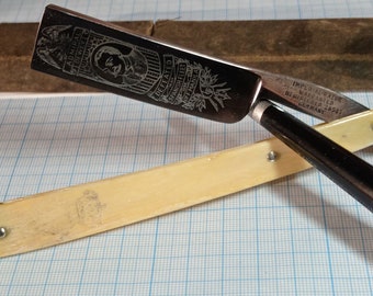 May include: A silver straight razor with a black handle and a bone-colored case. The razor is engraved with the words "Admiral Dewey Defeated Spanish Fleet May 1, 1898 Off Manila" and an image of Admiral Dewey. The case is engraved with the words "Imperial Razor Warranted Registered 26507 Germany."