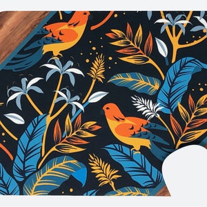 Peut inclure: Un tapis de souris avec un motif tropical représentant des feuilles bleues, orange et jaunes et des oiseaux sur un fond bleu foncé.