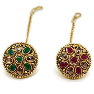 Puede incluir: Dos anillos de nariz de oro con cadenas colgantes. Un anillo tiene piedras preciosas verdes y el otro tiene piedras preciosas rojas.