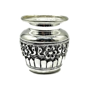 May include: A silver pot with a floral design. The pot has a wide mouth and a narrow base. It is decorated with intricate floral patterns.