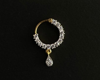 May include: A gold nose ring with a teardrop-shaped pendant, both adorned with clear cubic zirconia stones.