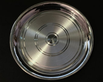 May include: A silver serving platter with a circular design and a shiny, polished finish.