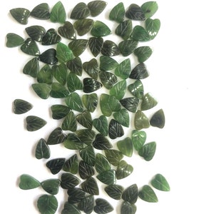 Può includere: Una collezione di perline di giada verde a forma di foglia. Le perline sono intagliate con venature di foglie dettagliate e hanno una finitura liscia e lucida.