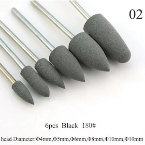 Puede incluir: Seis bandas de lijado grises con grano negro, que van desde 4 mm hasta 10 mm de diámetro. Las bandas de lijado están unidas a ejes metálicos. El texto "6pcs Black 180#" y "head Diameter: 4mm, 5mm, 6mm, 8mm, 10mm, 10mm" está impreso debajo de las bandas de lijado.