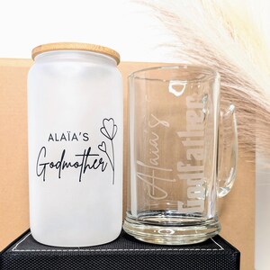 Pu&ograve; includere: Un barattolo di vetro smerigliato con un coperchio in bamb&ugrave; e una tazza di vetro. Il barattolo ha il testo "Ala&iuml;a's Godmother" e un piccolo disegno di un fiore. La tazza ha il testo "Ala&iuml;a's Godfather" inciso su di essa.