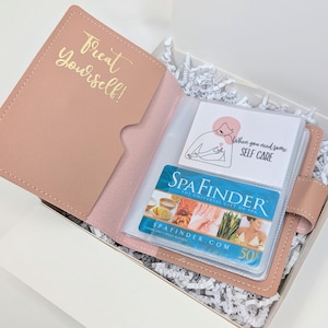 May include: A pink gift box with a pink leatherette pouch that says "Treat Yourself!" inside. The pouch contains a clear plastic card holder with a gift card for Spafinder and a card that says "When you need some self care".