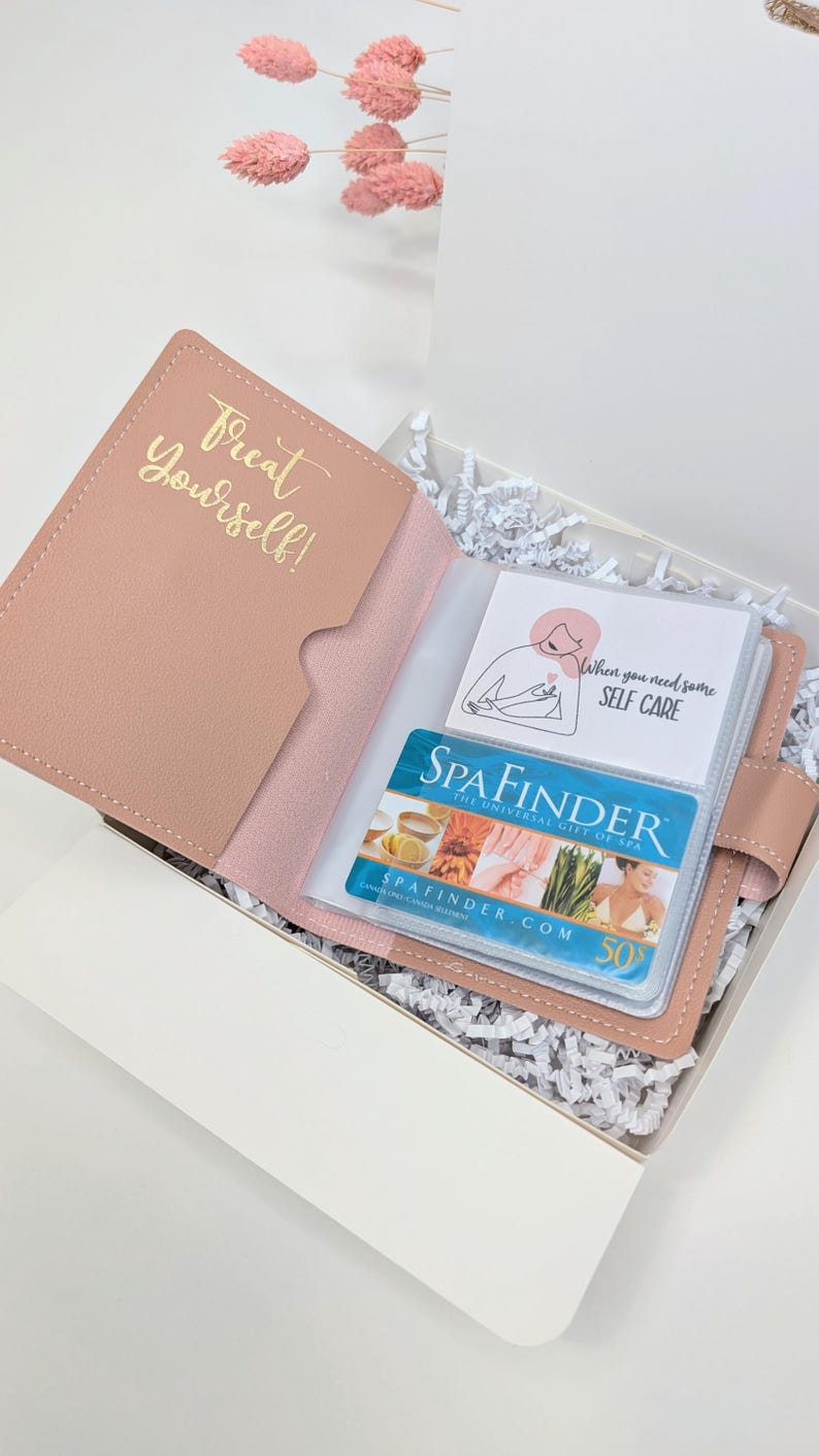 May include: A pink gift box with a pink leatherette pouch that says "Treat Yourself!" inside. The pouch contains a clear plastic card holder with a gift card for Spafinder and a card that says "When you need some self care".