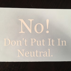 Puede incluir: Una pegatina azul claro con las palabras "No! Don't Put It In Neutral" en blanco, con fuente serif. La pegatina es rectangular y el texto está centrado.