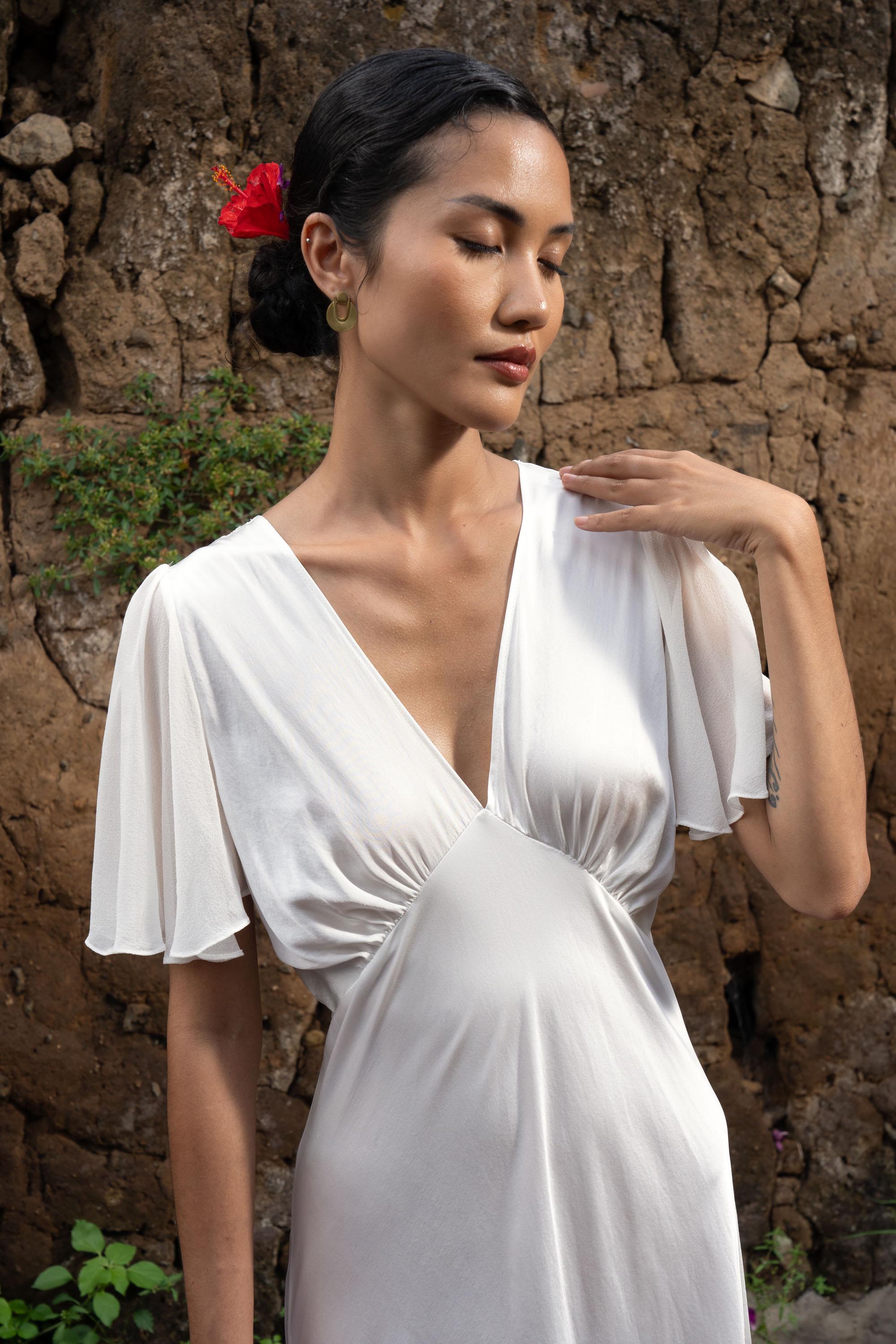 white silk dress dyed with tiger butterflies and waves detail A white dress transformed through the ancient art of tiedye: butterflies shaped with clamps, fabric folded and bound, dipped again and again in indigo and rinsed until patterns emerge. The result is