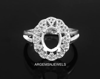 May include: Silver ring setting with an oval shaped center stone. The setting features a delicate floral design with small stones around the perimeter.