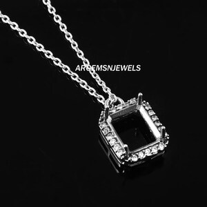 Peut inclure: Un collier avec un pendentif en argent, composé d'un serti carré entouré de petites pierres claires. Le pendentif est suspendu à une fine chaîne en argent.