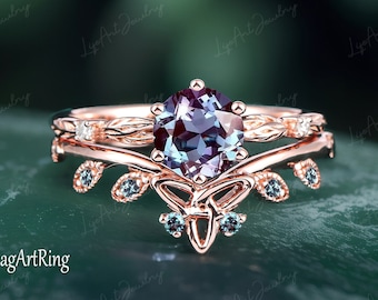 May include: A rose gold engagement ring set with a large, round, iridescent alexandrite gemstone surrounded by smaller alexandrite stones. The ring features a delicate, leafy design with a Celtic knot motif.