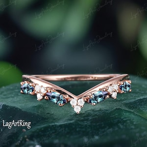 Può includere: Una fede nuziale in oro rosa con un design a forma di V che presenta una fila di pietre blu a forma di marquise e diamanti bianchi rotondi.