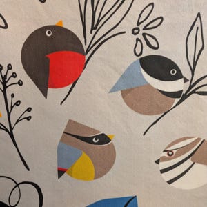 May include: A gray background with a stylized illustration of birds. The birds are drawn in a geometric style with different colors and patterns. The birds are surrounded by black and white floral designs.