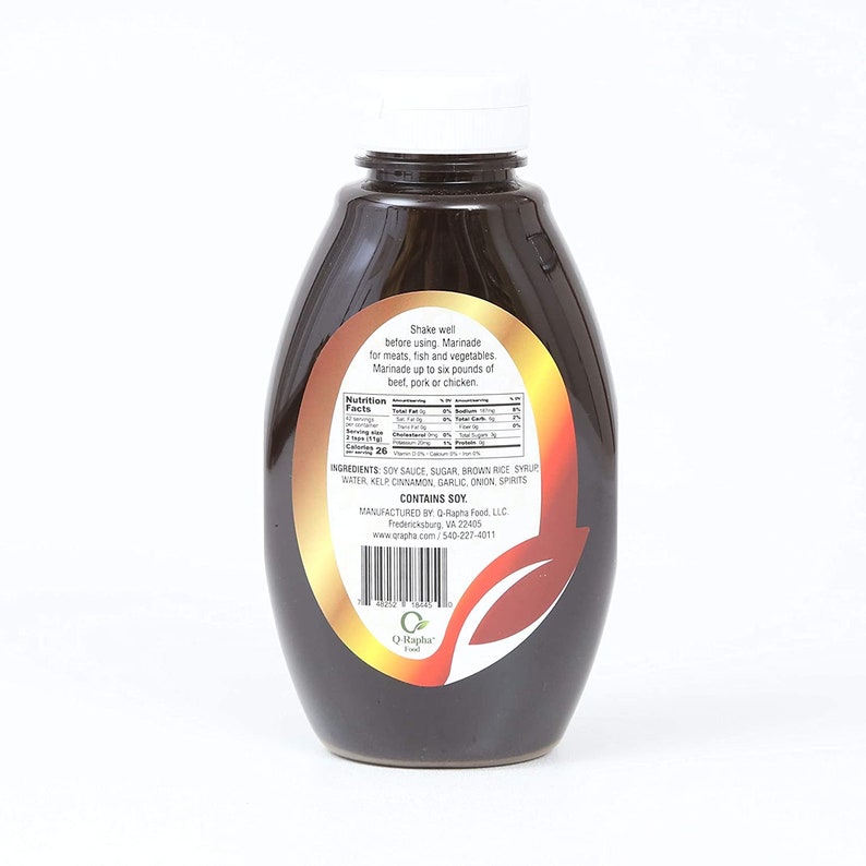 May include: A brown glass bottle of Q-Rapha marinade with a white cap. The label is yellow with brown text and a brown leaf design. The label reads "Shake well before using. Marinade for meats, fish and vegetables. Marinade up to six pounds of beef, pork or chicken." The ingredients are listed on the label: "Soy Sauce, Sugar, Brown Rice Syrup, Water, Kelp, Cinnamon, Garlic, Onion, Spirits. Contains Soy."