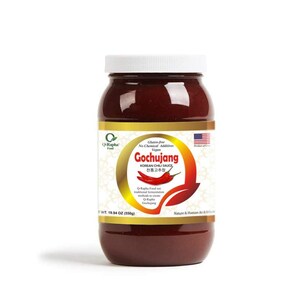 K&ouml;nnte beinhalten: Ein Glasgef&auml;&szlig; mit roter Gochujang Koreanischer Chillisauce und einem wei&szlig;en Deckel. Das Etikett ist golden mit einem gr&uuml;nen Blattdesign und dem Text "Gochujang Korean Chili Sauce" in Schwarz. Das Etikett enth&auml;lt auch den Text "Glutenfrei, Keine chemischen Zus&auml;tze, Vegan" in kleinerer Schrift. Das Glas steht auf einer wei&szlig;en Oberfl&auml;che.
