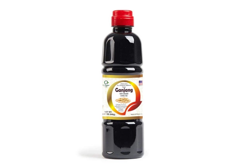 Puede incluir: Una botella de 500 ml de salsa de soja Ganjang. La botella es negra con una tapa roja y una etiqueta blanca con las palabras "Ganjang Soy Sauce" en texto negro. La etiqueta tambi&eacute;n presenta una imagen de soja.