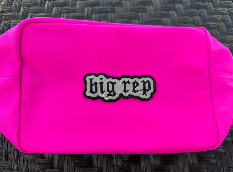 Op de afbeelding: Een felroze ritsvak met een zwart en zilveren patch waarop "big rep" staat