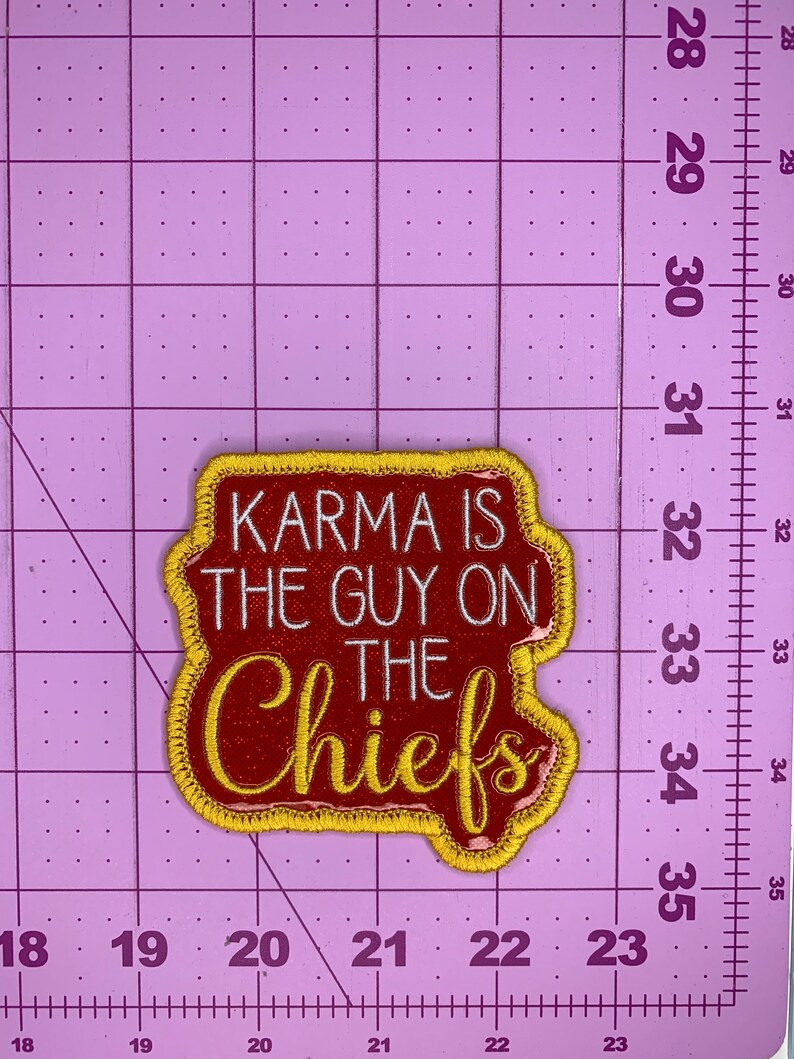 May include: A red and gold embroidered patch with the text "KARMA IS THE GUY ON THE CHIEFS" in white lettering.
