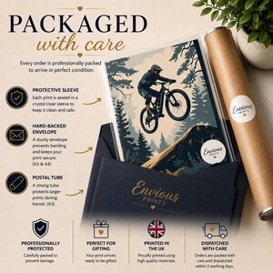 Puede incluir: Una l&aacute;mina art&iacute;stica de un ciclista de monta&ntilde;a saltando sobre una colina en un bosque. La l&aacute;mina est&aacute; dentro de una funda protectora transparente, colocada en un sobre azul oscuro y acompa&ntilde;ada de un tubo postal de cart&oacute;n marr&oacute;n.
