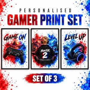 May include: A set of three wall art prints featuring red and blue watercolour splatter effects. The prints display the text "PERSONALISED GAMER PRINT SET", "GAME ON", "LEVEL UP", and "SET OF 3", alongside illustrations of a game controller, a gamer, and headphones.