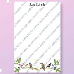 May include: A rectangular white notepad featuring the name June Estrella at the top and a row of various colourful birds perched on a branch at the bottom. The paper is covered in a repeating diagonal watermark of the text Stellar Jotter.